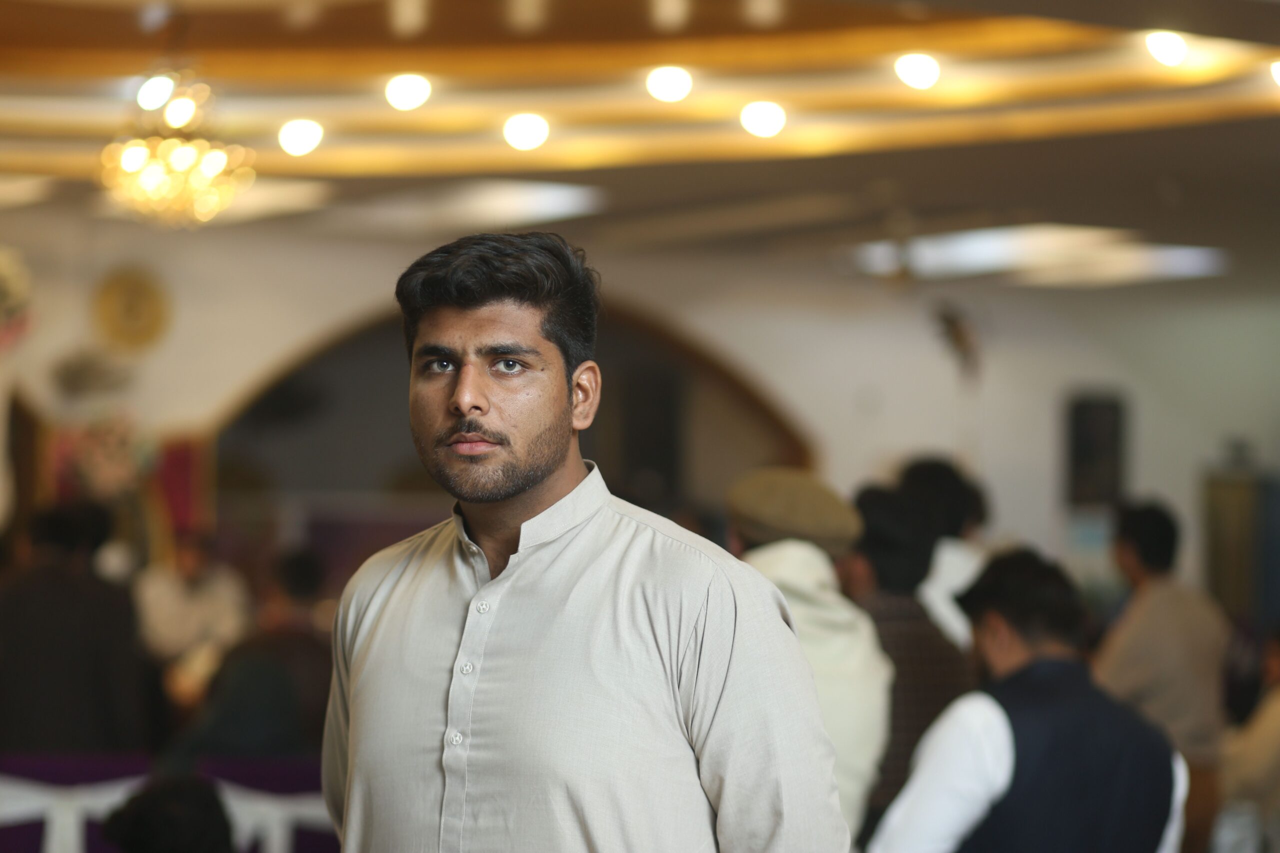 Home Young man in traditional attire at a social gathering in Sheikhupura, Pakistan.